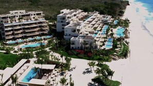 Un resort con varias edificaciones, una playa y varias piscinas.