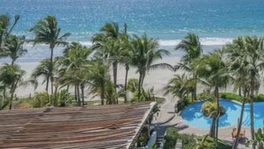 Un resort con piscina, palmeras y vista al océano.