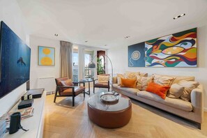 En moderne stue med sofa, lænestole, sofabord og kunst på væggene.