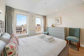 A hotel room with a bed, a chair, a dresser, and a window with a view of buildings.