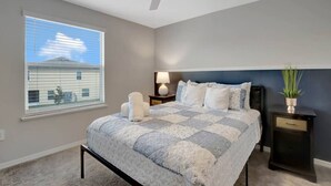 Ein Schlafzimmer mit einem Bett, Nachttischen, einem Deckenventilator und einem Fenster mit Jalousien.