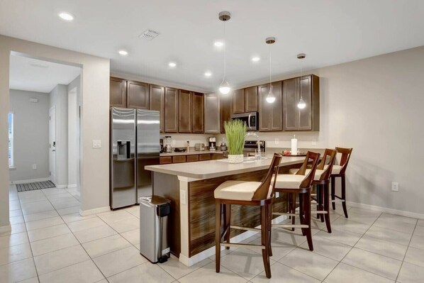 A modern kitchen with a central island, stainless steel appliances, and bar stools.