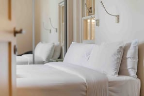 A hotel room with a large bed, a bedside table, and a mirror on the wall.