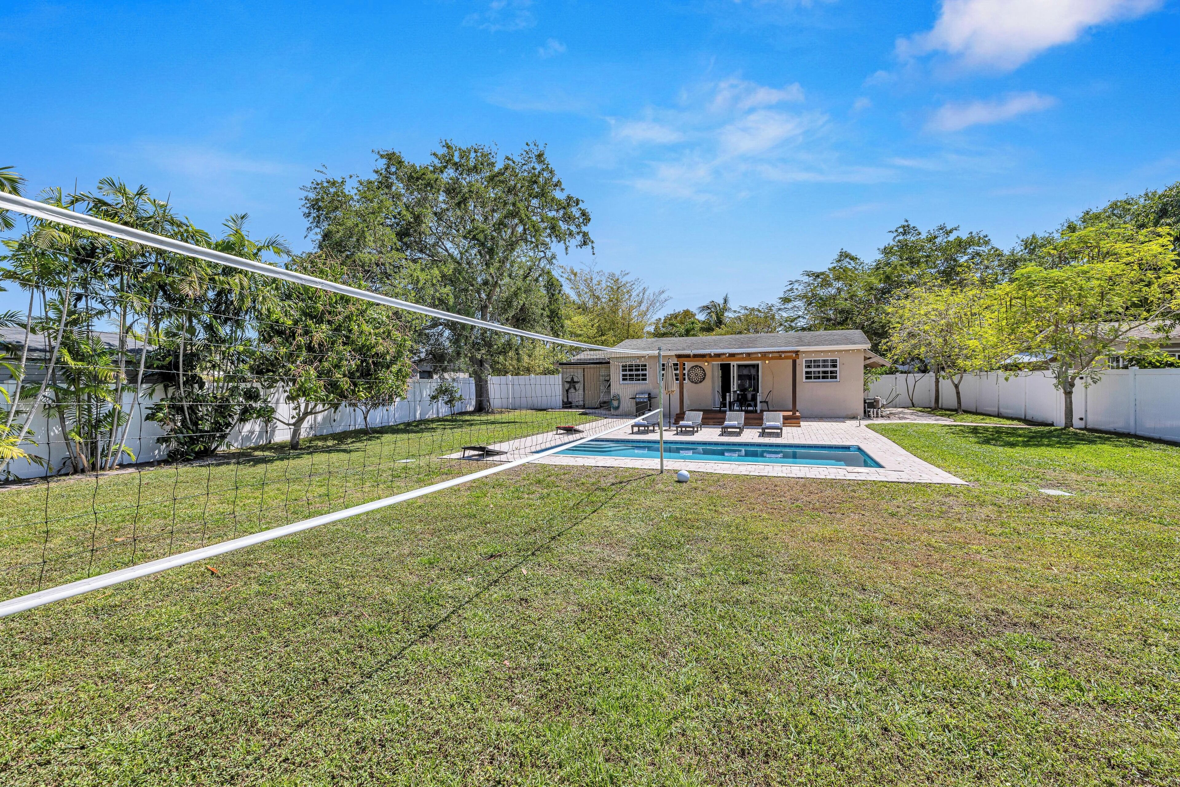 A backyard with a swimming pool, a small house, and a fenced area.