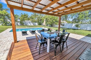 Eine überdachte Außenveranda mit Billardtisch, Stühlen und Pool.
