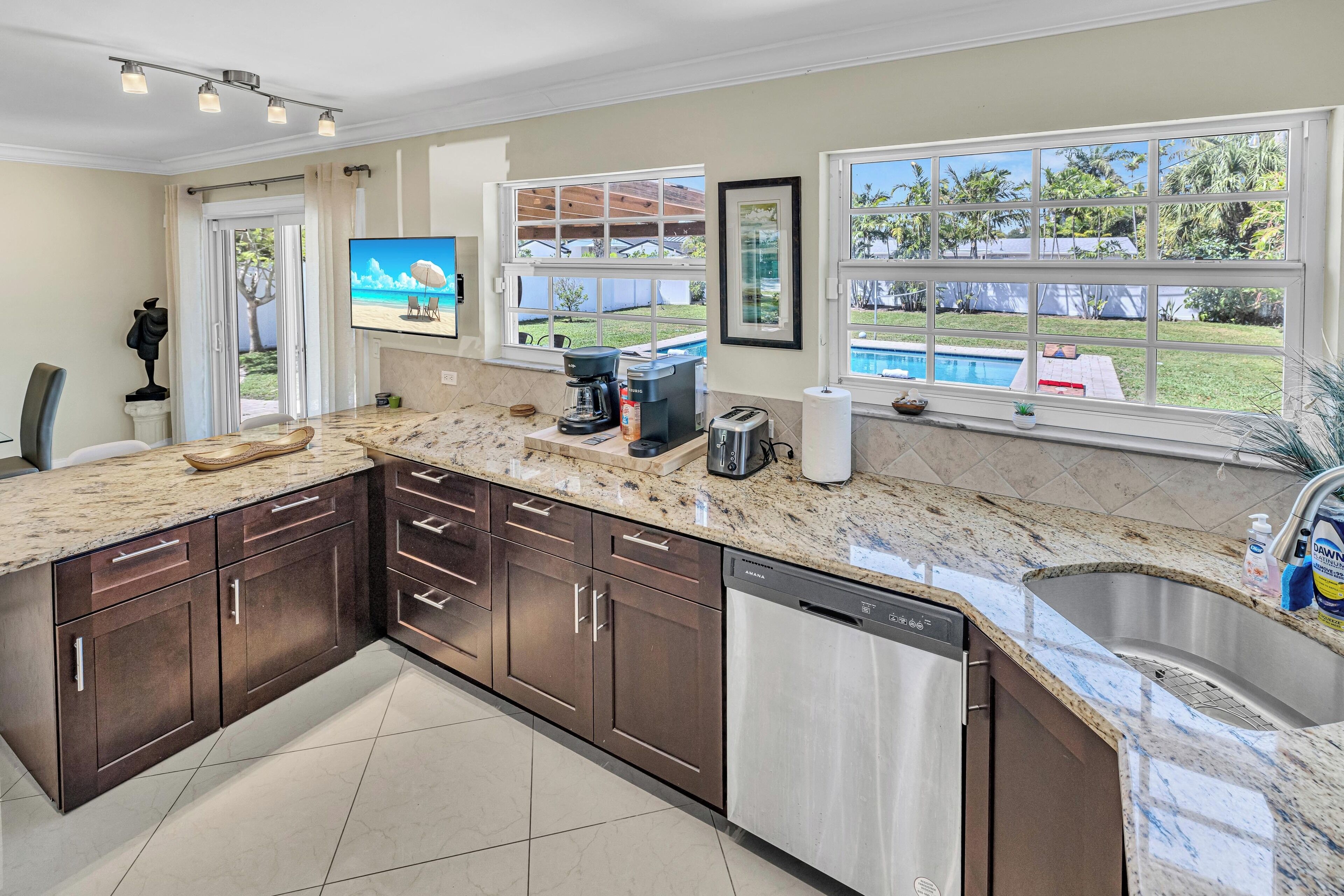 A modern kitchen with dark cabinets, a granite countertop, and a dishwasher.