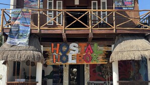A rustic hostel with a thatched roof and wooden facade, featuring a prominent 'HOSTAL' sign and a bicycle parked in front. - hostal casa holbox (Isla Holbox)