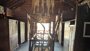 A rustic interior with a high ceiling, wooden beams, and a central wooden structure. - hostal casa holbox (Isla Holbox)