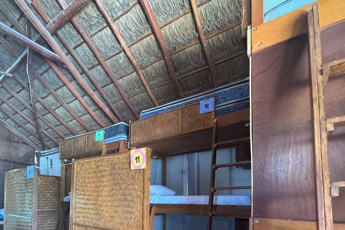 Bunk beds with numbered tags, a ladder, and a thatched roof structure.