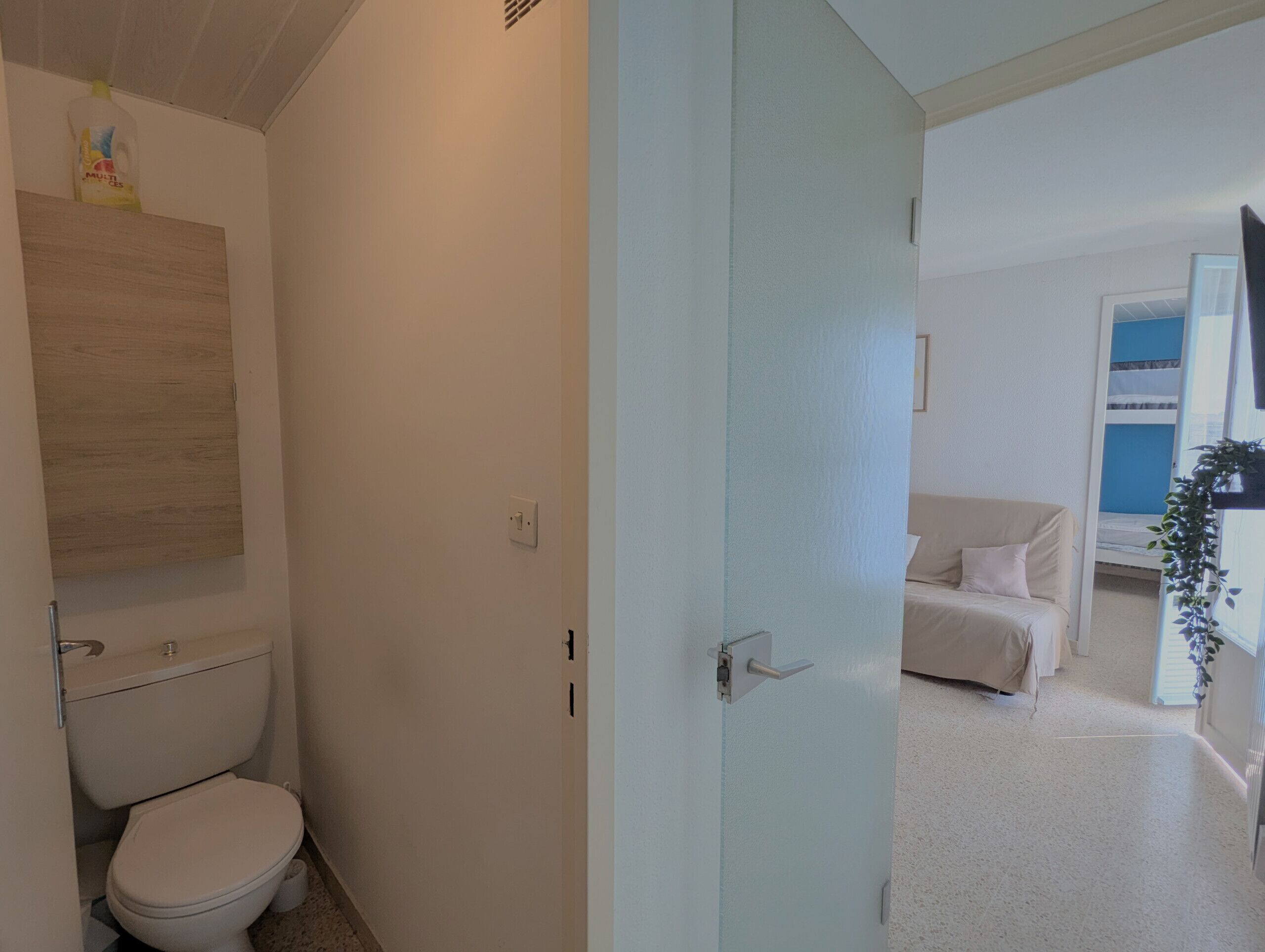 A modern bathroom with a toilet, a wooden panel, and a light switch.