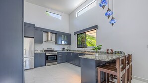 Una cocina moderna con gabinetes grises, electrodomésticos de acero inoxidable y una isla grande con taburetes de bar.