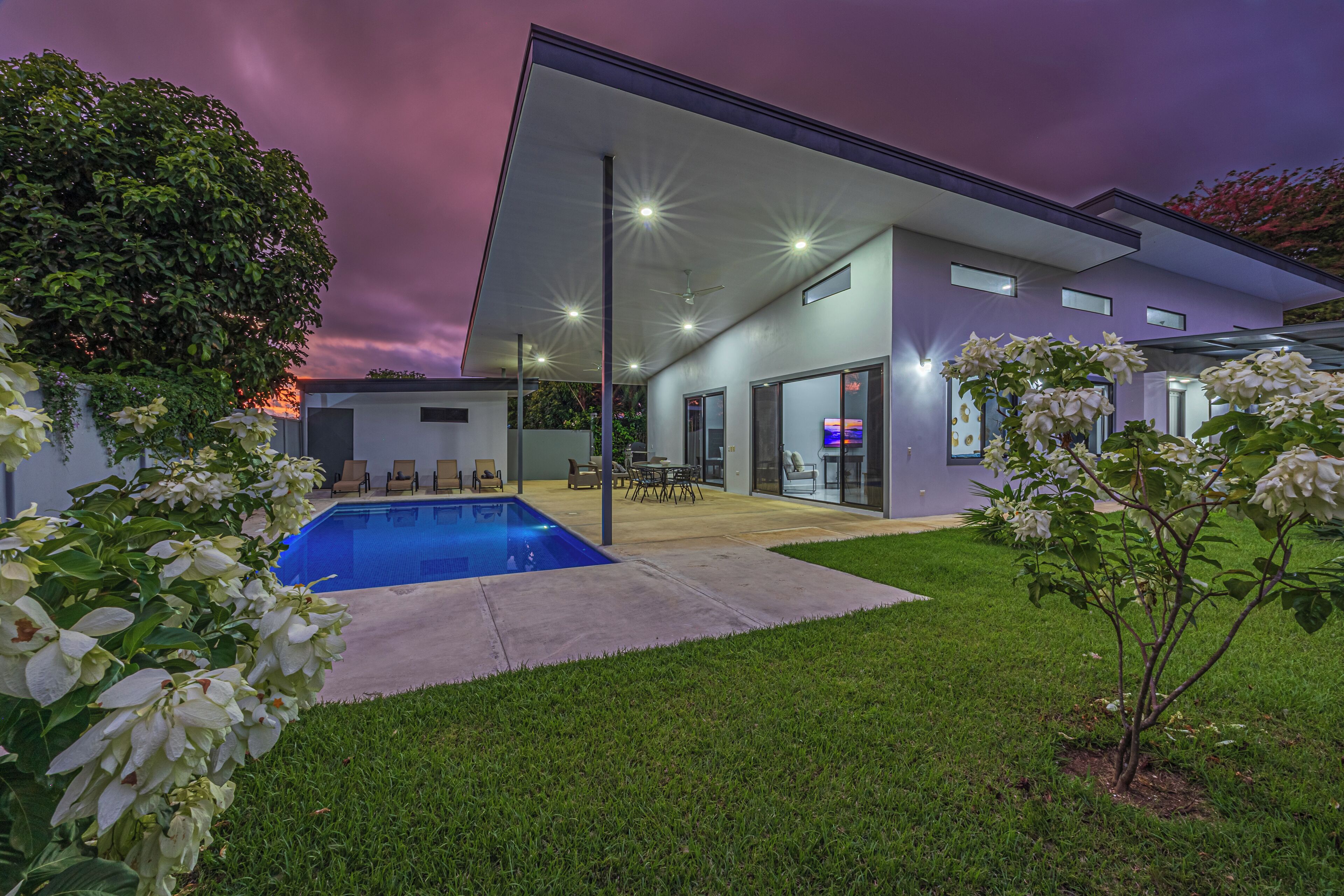 Ein modernes Haus mit Schwimmbad, Terrasse und gepflegtem Rasen.