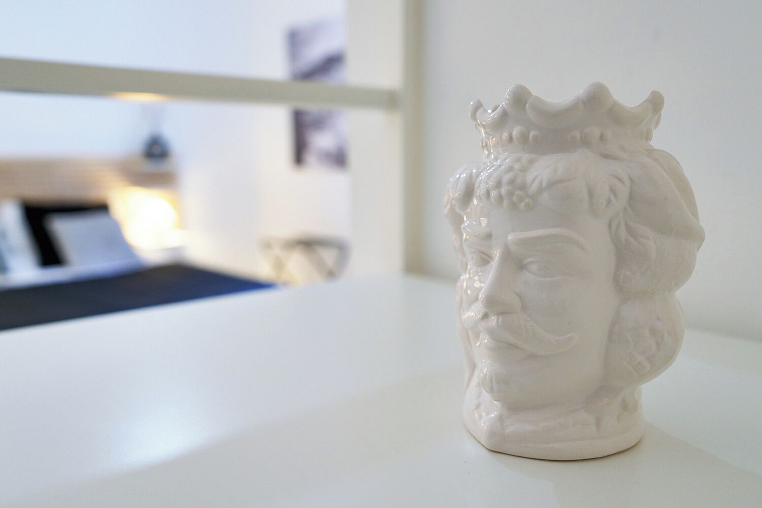 Une sculpture en buste blanche, posée sur une surface blanche.