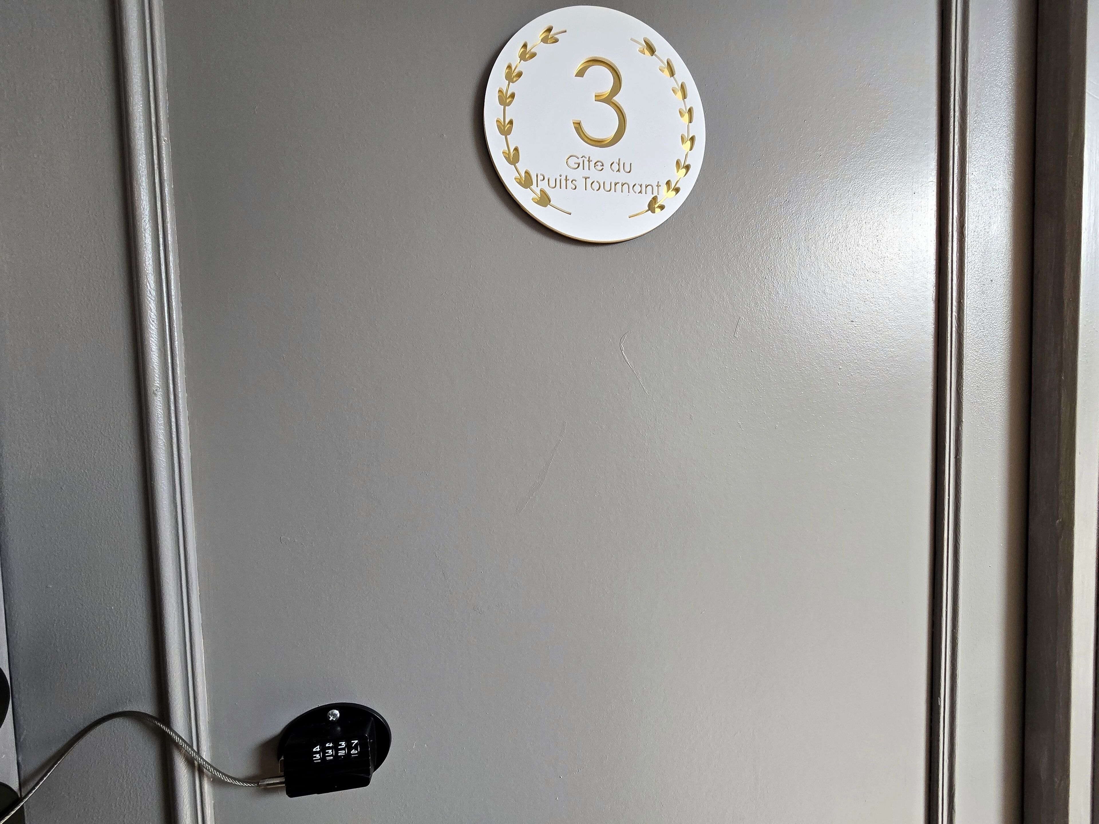 Una porta con una targa che indica il numero 3, una targhetta con testo e una presa elettrica con un cavo inserito.