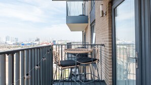 A balcony with a table and chairs, a view of the cityscape, and a glass door. - Stylish Flat Near Charlton Station - Pass the Keys (London)
