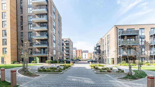 A modern apartment complex with multiple floors, balconies, and a central paved walkway. - Stylish Flat Near Charlton Station - Pass the Keys (London)