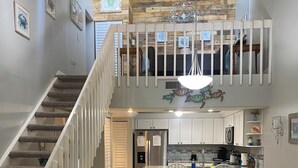 Una cocina amplia con una isla central, armarios blancos y un comedor con mesa y sillas.