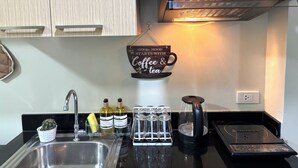 A kitchen with a coffee and tea sign, a sink, a stove, and a cabinet above.