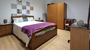 A modern bedroom with a bed, wooden wardrobe, and a desk. - Casa Laranjeira in the historic city (Faro)