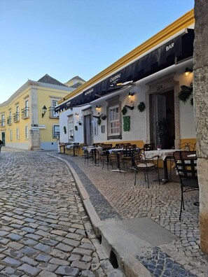 A cobblestone street with outdoor seating at a restaurant named 'CANTINHO'. - Casa Laranjeira in the historic city (Faro)