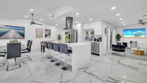 Una cocina moderna con una isla central, taburetes de bar y un comedor con mesa y sillas.