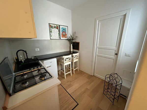 Een koelkast, een kookplaat, kookgerei, borden en bestek, kruiden