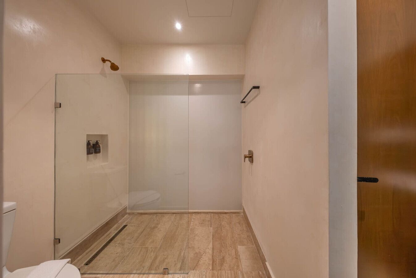 A bathroom with a glass shower enclosure, a toilet, and a sink.