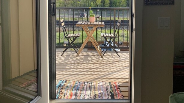 A room with a sliding glass door leading to an outdoor deck with a table and chairs, a view of mountains, and a framed picture on the wall.