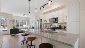 A modern kitchen with white cabinets, stainless steel appliances, and a large island with stools.
