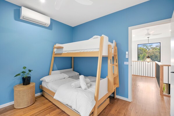 A bunk bed room with a ceiling fan, a potted plant, and a view of the outdoors through a window.