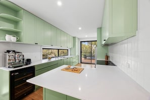 A modern kitchen with green cabinets, a white countertop, and a view to the outside. - Gully & Tide (Aireys Inlet)