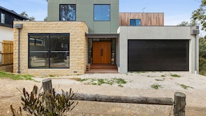 A modern two-story house with a garage, large windows, and a stone facade.