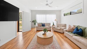 A modern living room with a flat-screen TV, two sofas, a coffee table, and a ceiling fan.