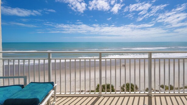Ein Balkon mit Blick auf Strand und Meer.