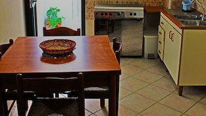 A compact kitchen with a dining table, chairs, a stove, and cabinets. - Antica Dimora (Sannicola)