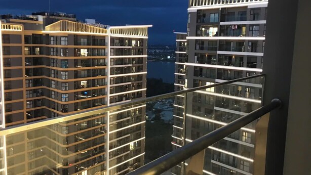 A high-rise building with multiple balconies and a view of a body of water at night. - Rose Vinhomes (Ho Chi Minh City)
