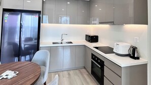 A modern kitchen with a built-in oven, microwave, and a coffee maker on the counter. - Rose Vinhomes (Ho Chi Minh City)