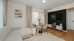 A modern living room with a sofa, a dining table with chairs, a flat-screen TV, and a decorative vase.