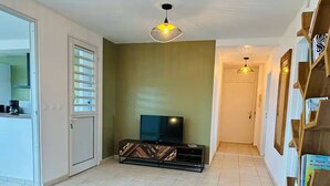 A living room with a sofa, coffee table, TV, and two pendant lights. - SAINTE LUCE A STONE'S THROW FROM THE BEACH (Sainte-Luce)
