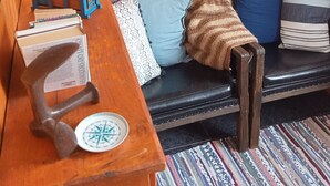 A cozy room with wooden walls, a wooden bench, a patterned rug, and a ship painting on the wall. - Charming 1-bedroom apartment in amazing Angra do Heroísmo with WiFi (Angra do Heroísmo)