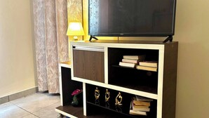 Un mueble moderno de entretenimiento con televisor de pantalla plana, estanterías y objetos decorativos.