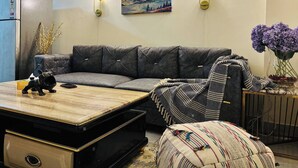 Una sala de estar moderna con un sofá gris, una mesa de centro de madera y un cuadro de un paisaje montañoso.