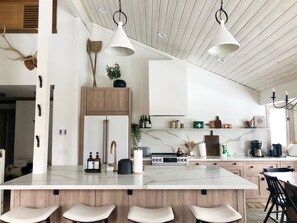 Une cuisine moderne dotée d’un îlot central, de meubles en bois et de luminaires suspendus.