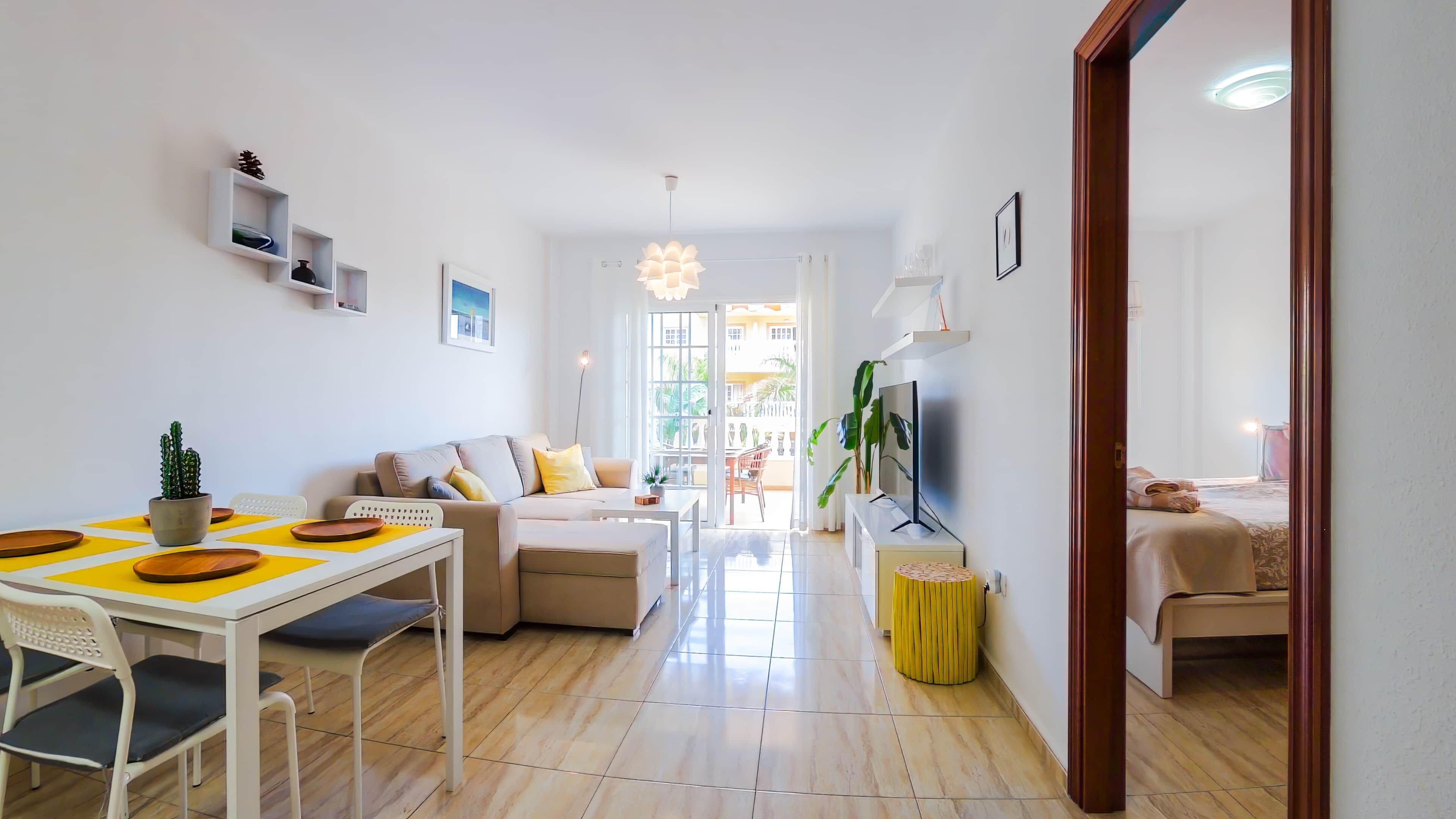 Una sala de estar moderna con sofá, mesa de comedor y televisor.