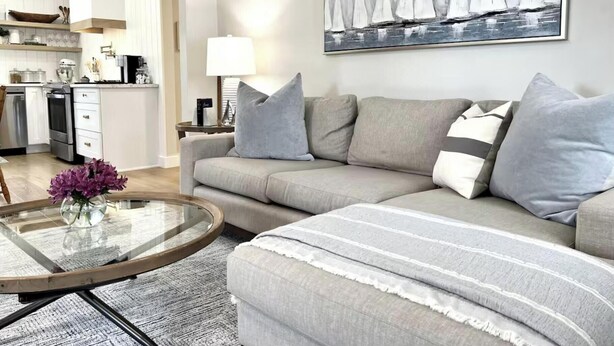 A modern living room with a grey sofa, a glass coffee table, and a painting of sailboats on the wall. - The Driftwood, Saint Andrews (St. Andrews)