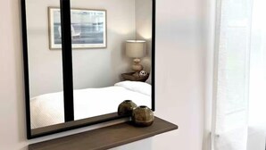 A hotel room with a bed, a bedside table with a lamp, and a shelf with two vases. - The Driftwood, Saint Andrews (St. Andrews)