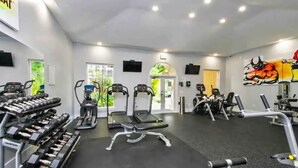 A gym with various exercise equipment, including treadmills, elliptical machines, and dumbbells.