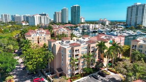 A marina with boats, surrounded by multi-story residential buildings with red roofs and balconies.