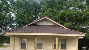 A single-story house with a front porch, a number '201' on the door, and a small garden with yellow flowers. - Charming 2-bedroom house with AC, WiFi in the heart of Pembroke (Pembroke)