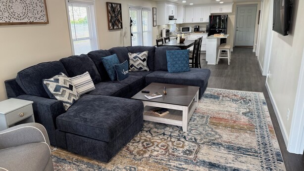 A modern living room with a sectional sofa, a coffee table, and a patterned rug. - Charming 2-bedroom house with AC, WiFi in the heart of Pembroke (Pembroke)